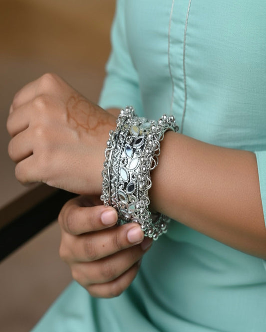 Close-up of a person wearing multiple silver bracelets on a blurred background